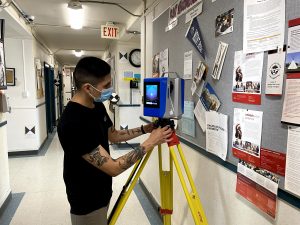Brendon Many Bears uses a laser scanner to digitally capture the main floor of Old Sun Community College