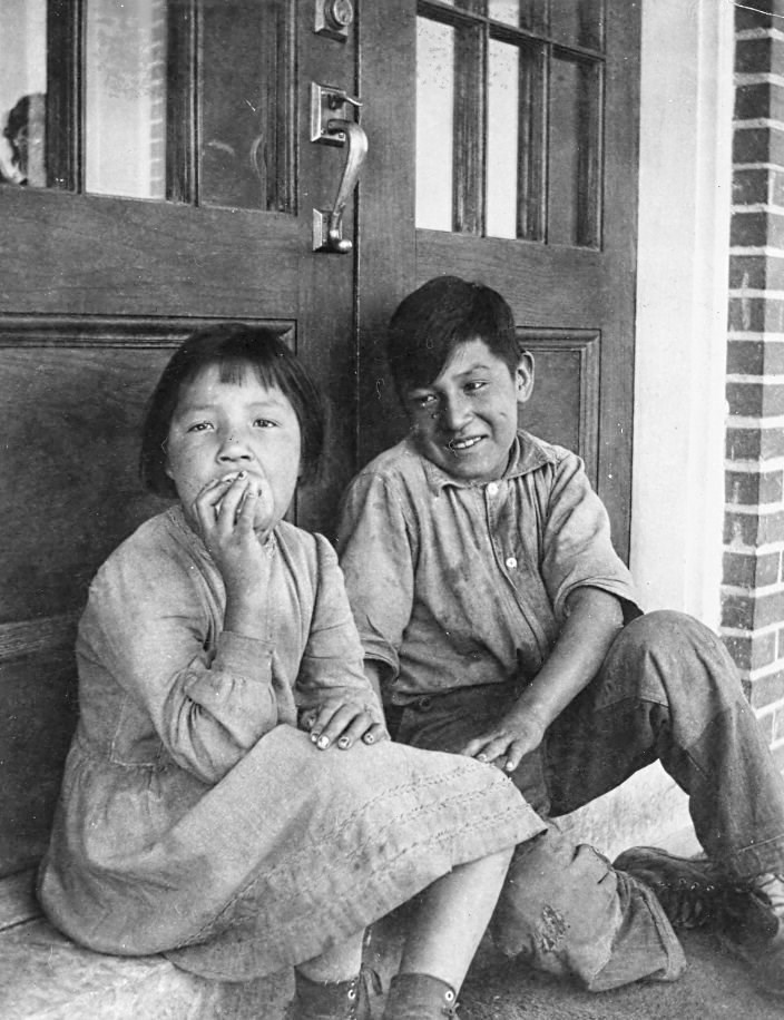 Sister and brother Audrey and Colin Stimson sitting outside the front entrance steps - [193-?]. P75-103-S7-194 from The General Synod Archives, Anglican Church of Canada