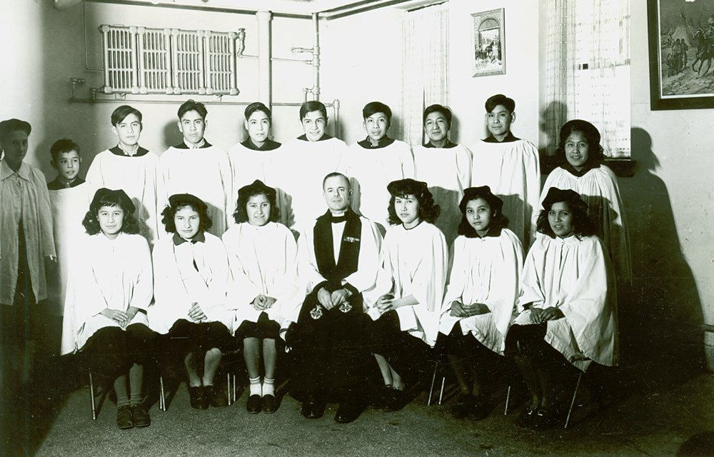 Old Sun Residential School, Gleichen, Alta. - Principal the Rev. E.S.W. Cole and Confirmation Class. Photo taken in student dining room - [194-?]. P75-103-S7-207 from The General Synod Archives, Anglican Church of Canada