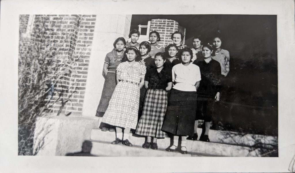 Choir girl on steps of the main school building, 1936. PR1985.0100 from The Provincial Archives of Alberta, Open Copyright.