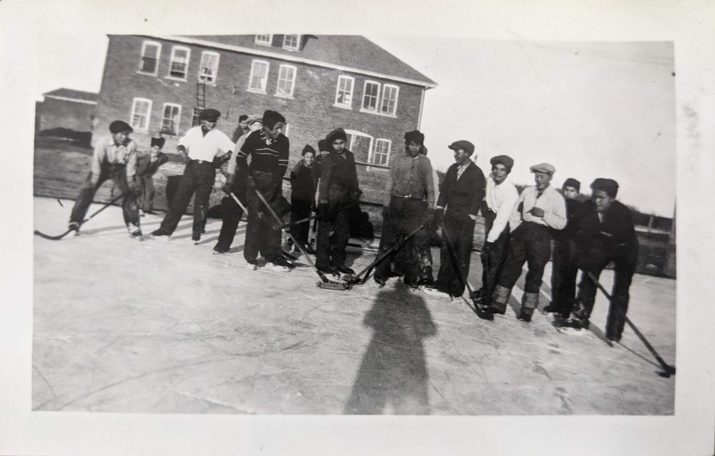 Playing hockey in front of the carriage house, 1936. PR1985.0100 from The Provincial Archives of Alberta, Open Copyright.