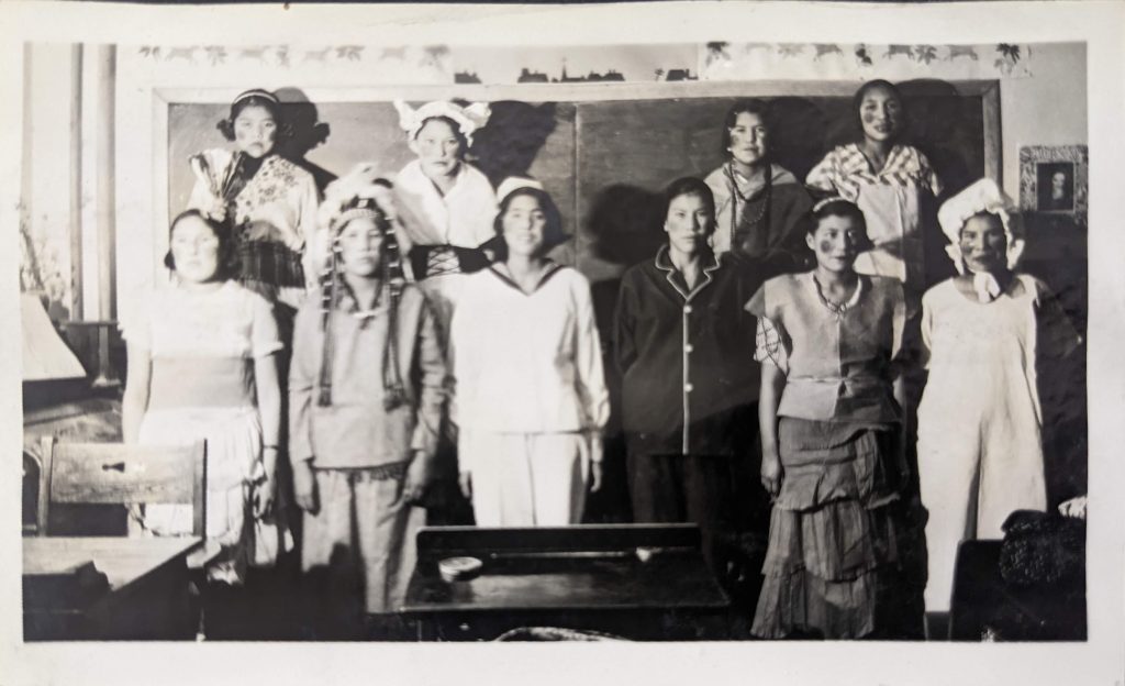 Students dressed up and photographed in front of a chalkboard in a classroom, between 1926-1937. PR1985.0100 from The Provincial Archives of Alberta, Open Copyright.