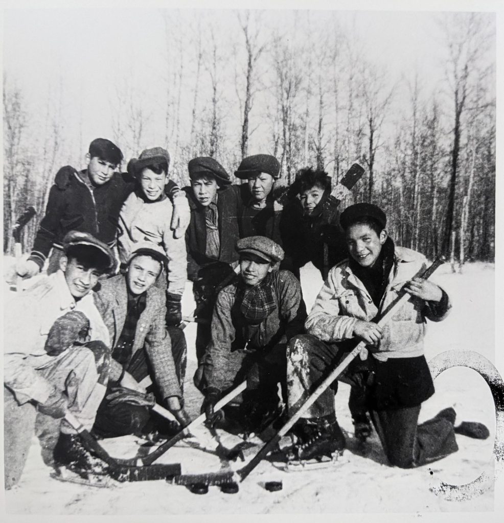 Boys playing hockey on the rink to the north of the school, 1950-1951. Hockey was very popular among students, and Blue Quills boasted an excellent team. OB10454 from The Provincial Archives of Alberta, Open Copyright.